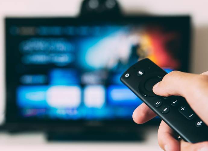 Person holding a remote in front of a smart TV interface