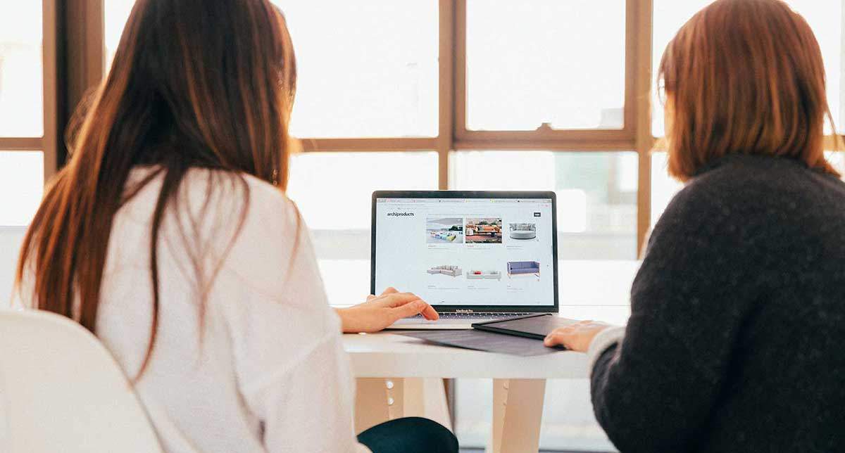 Two women looking at a laptop screen displaying a website during a demo meeting